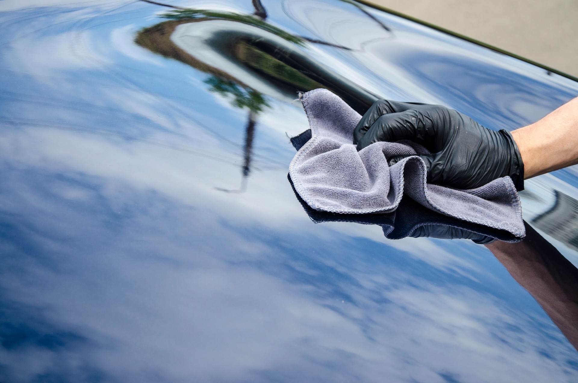 Car detailing - the man holds the microfiber in hand and polishes the car.